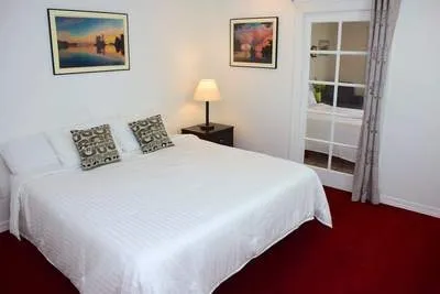 A bedroom with white walls and red carpet.