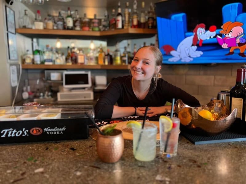 A woman sitting at the bar smiling for the camera.
